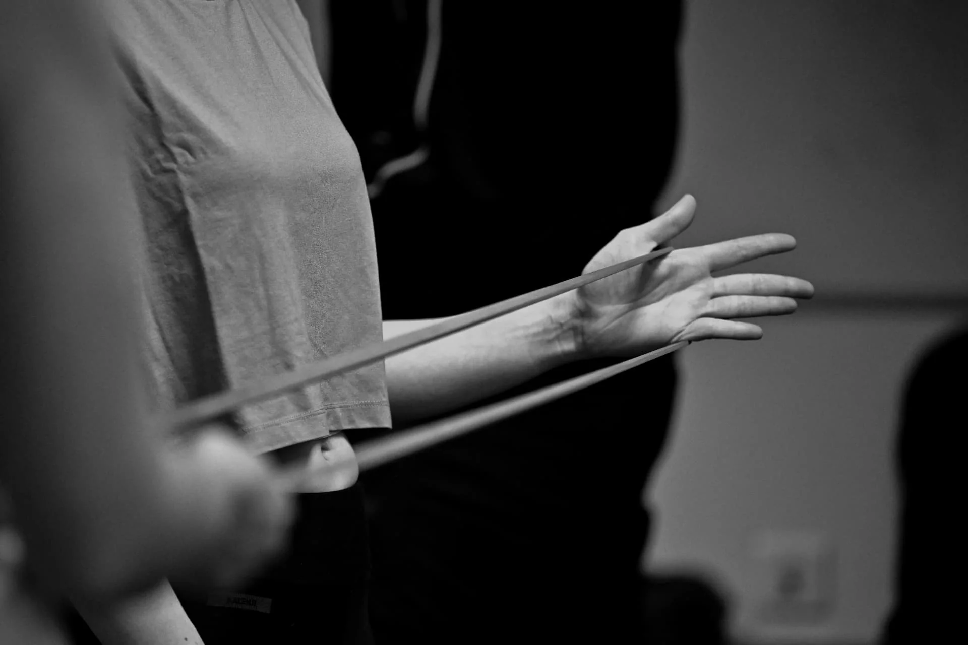 Une main ouverte et un élastique tendu, photographiés en noir et blanc.