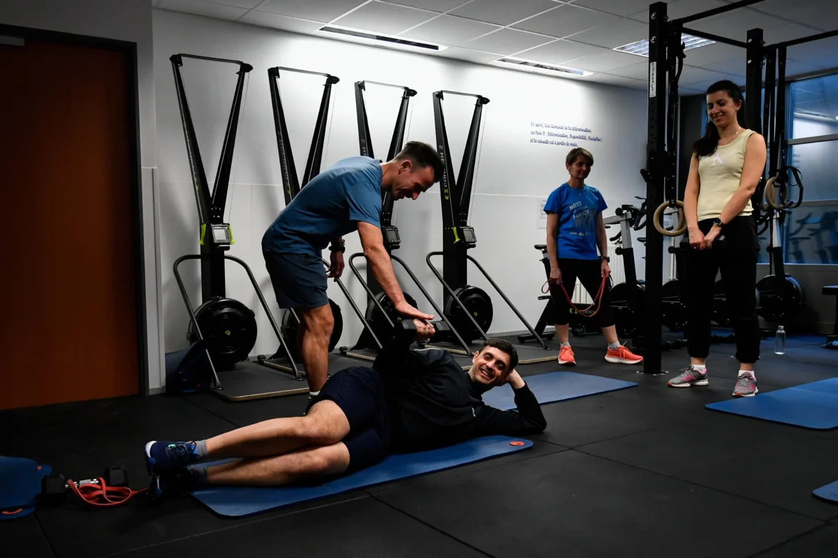 Benoît Jacquemin accompagne un participant allongé pendant un exercice, devant d'autres participants.