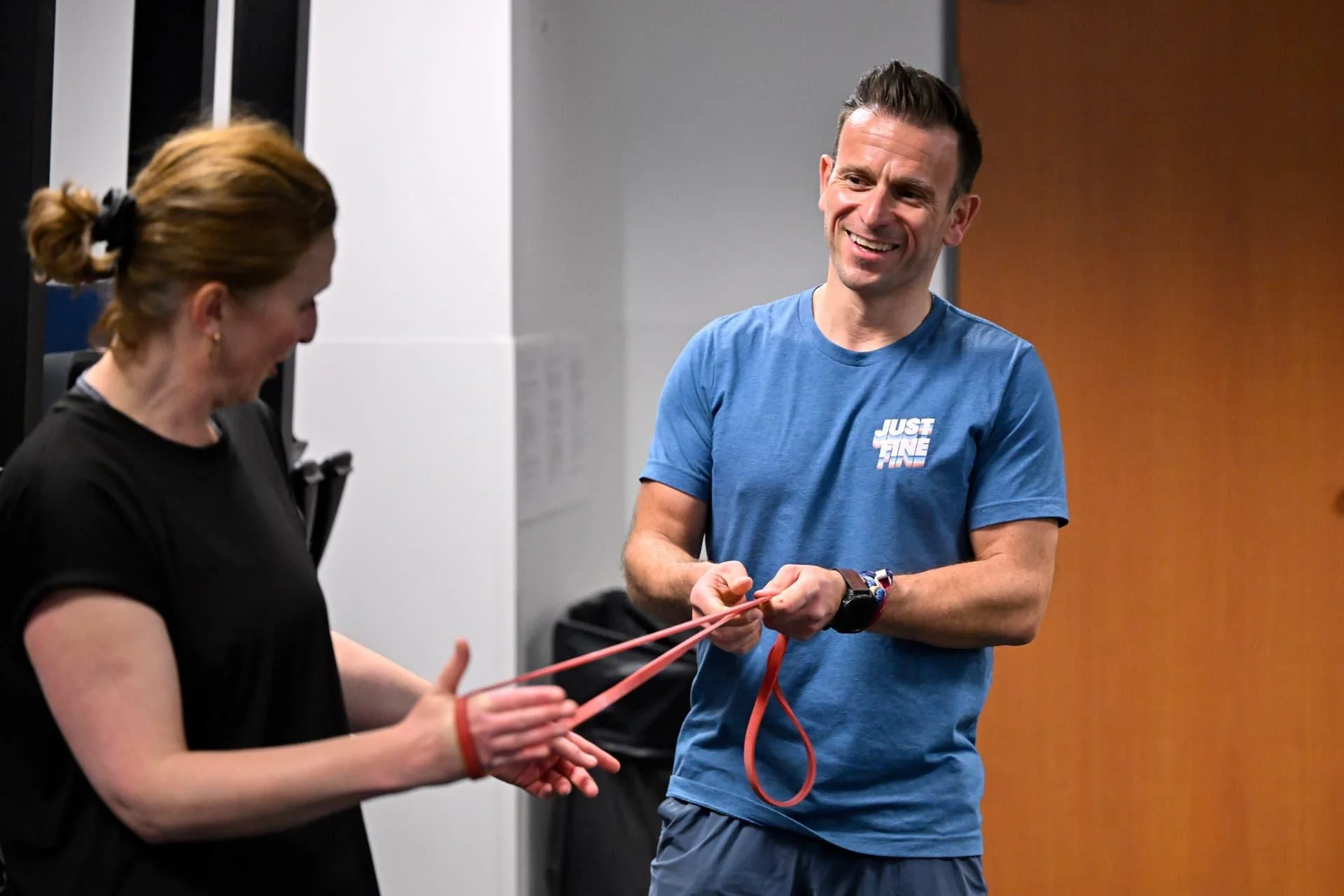 Benoît Jacquemin guide une participante dans un exercice avec un élastique rouge.